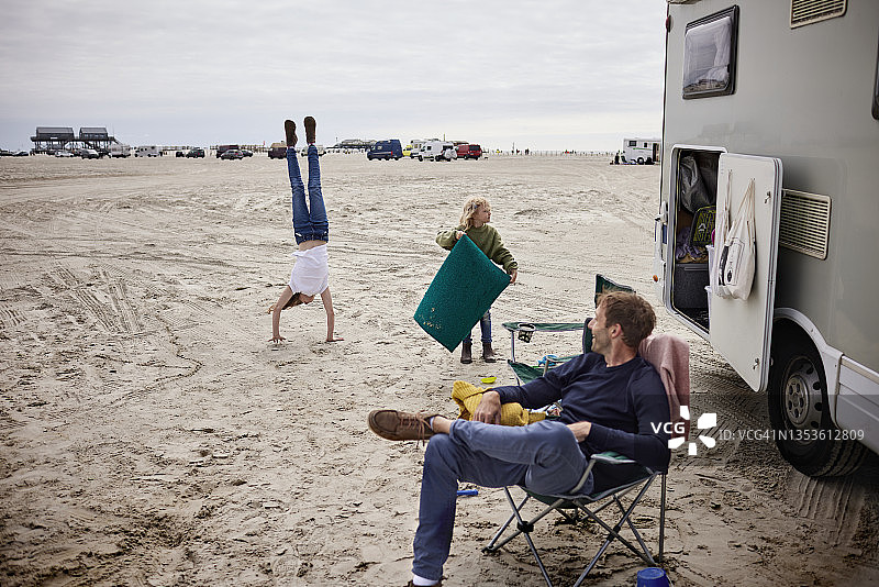 父亲带着两个女孩在沙滩上的露营车里图片素材