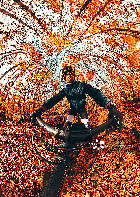 在西班牙秋天的森林里骑山地车的创意自拍。图片素材