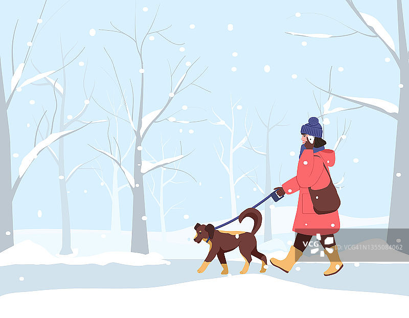 微笑的女孩在一个温暖的外套，帽子和手套遛狗在一个下雪的公园和讲电话。一条狗用皮带牵着走在她旁边。图片素材