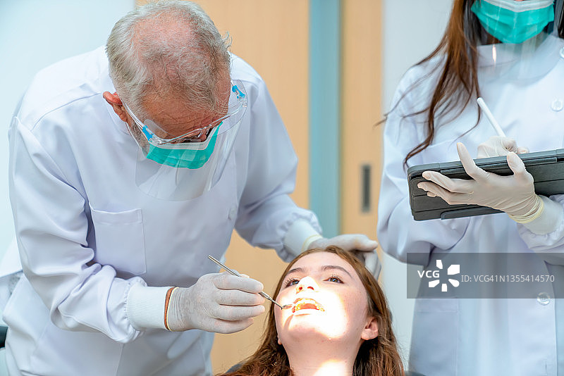 牙科医生正在手术室为女孩的牙齿进行牙科手术。图片素材