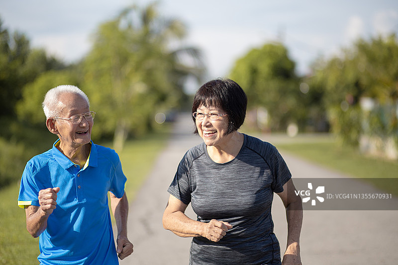 亚洲华人活跃的老年男子和妻子在早上一起在公园慢跑图片素材