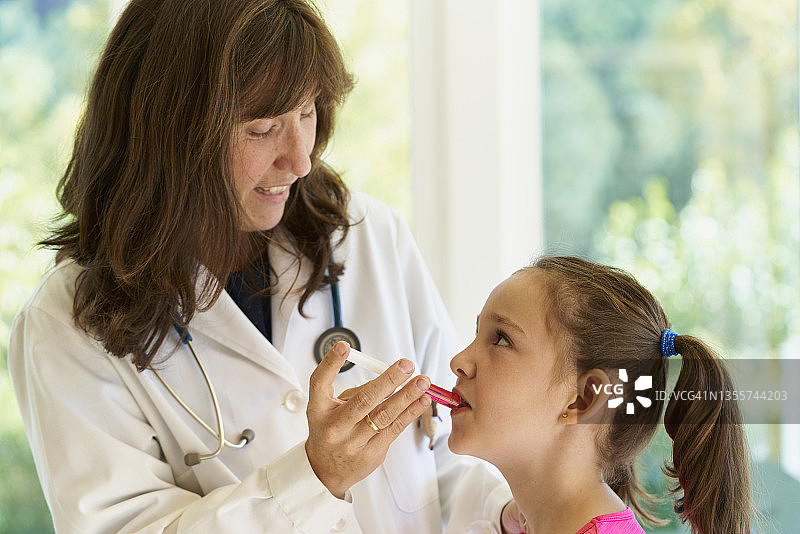 一位中年儿科女医生和她的小病人在给药时看着对方图片素材