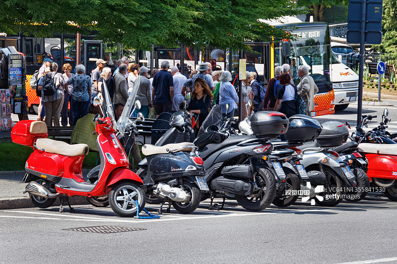红色意大利摩托车Vespa和其他两轮机动车辆在贝加莫街道上。图片素材