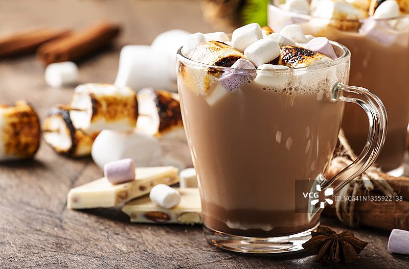 热巧克力饮料与炸棉花糖在玻璃杯子和冬天装饰木桌子。温馨的圣诞和新年假期的概念图片素材