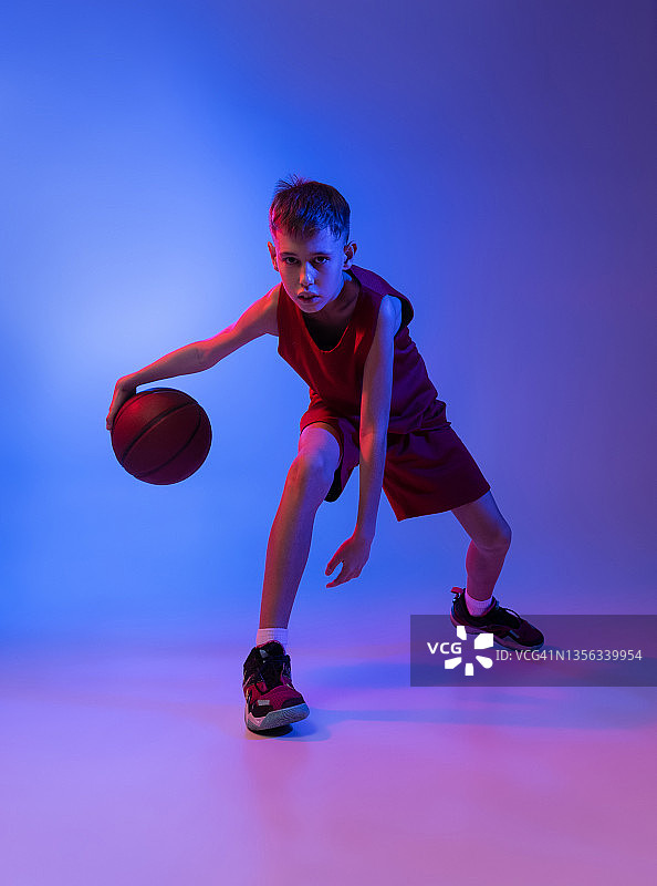 全长肖像的篮球运动员训练，运球孤立的梯度蓝色背景在霓虹灯图片素材