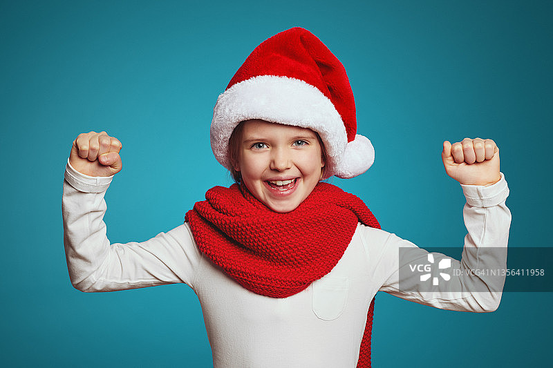 戴着圣诞帽和红围巾的女孩举起拳头庆祝图片素材