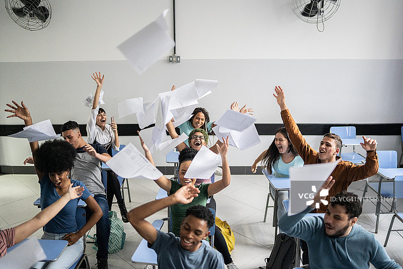 十几岁的学生在教室里向空中扔纸图片素材