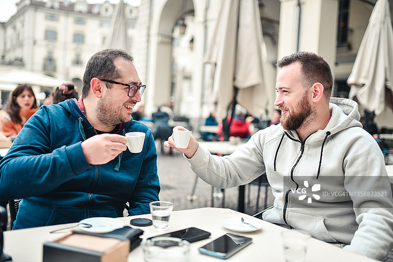 两个微笑的朋友在咖啡馆喝咖啡聊天图片素材