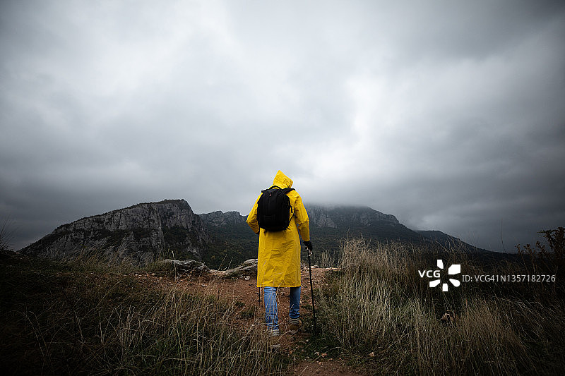穿着黄色雨衣爬山的徒步旅行者图片素材