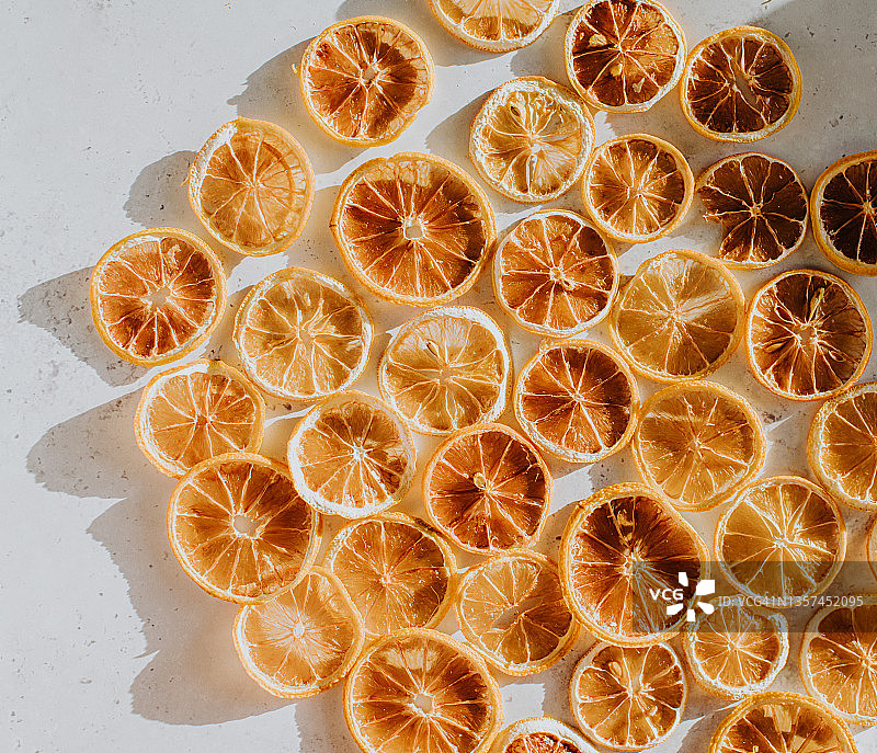 从上到下的概念背景图像，脱水的橙/柠檬/葡萄柚/柑橘片段在白色的表面上图片素材
