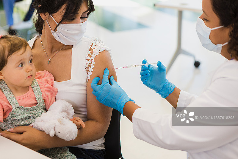 抱着女儿的单亲妈妈接种了新冠疫苗图片素材