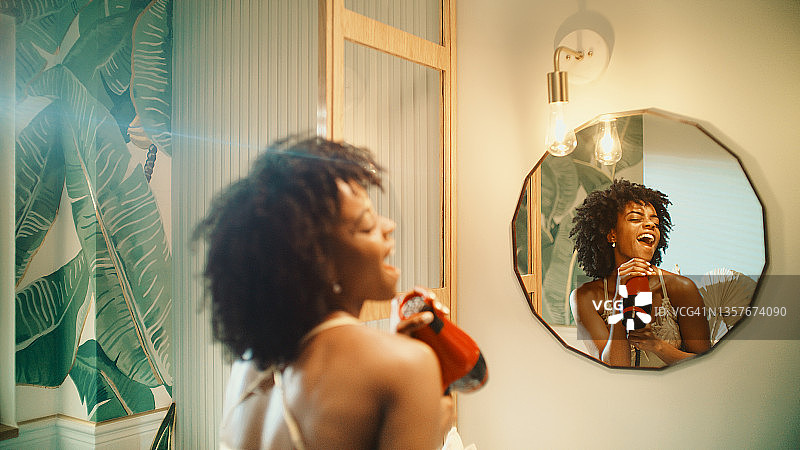 令人难以置信的感觉。非洲民族的妇女享受早晨的浴室例行公事和在镜子前有乐趣。晾干头发跳舞图片素材