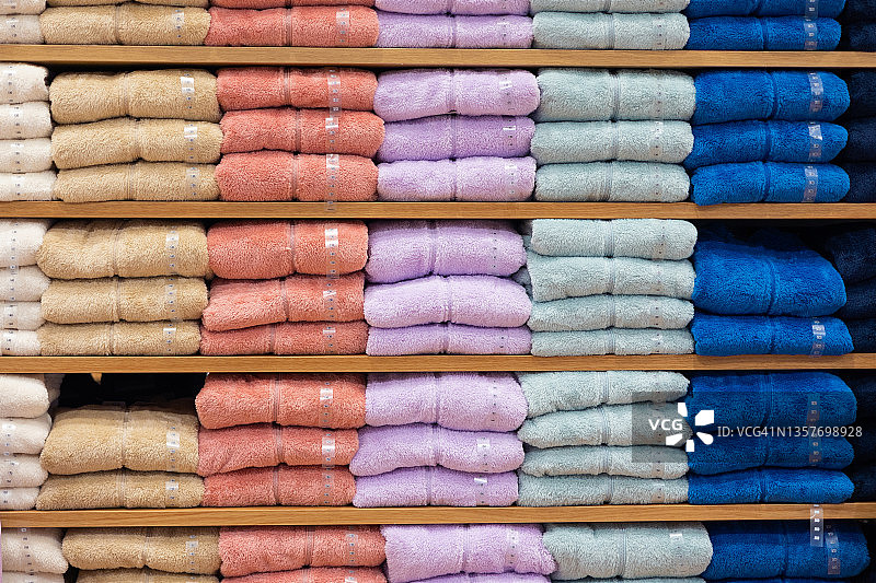 不同颜色的针织毛料衣服一堆堆地放在商店的货架上出售。图片素材