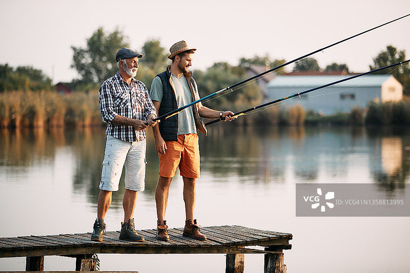长男子和他的儿子在码头上淡水钓鱼。图片素材