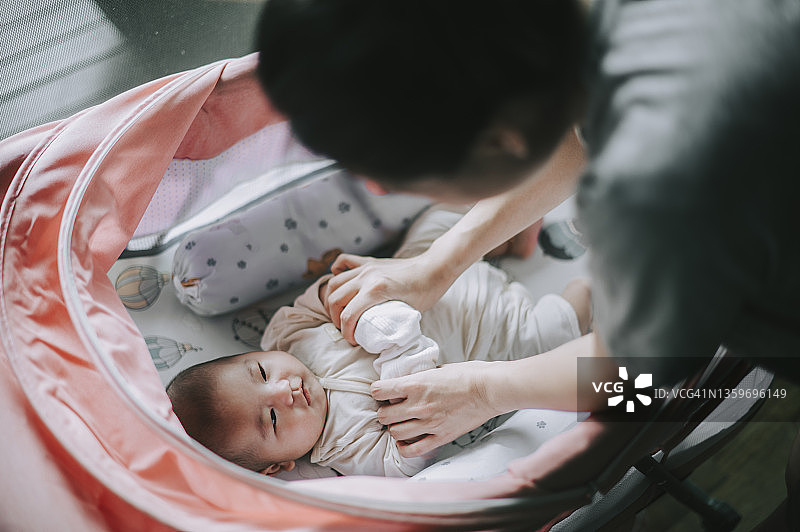 亚洲华人母亲与在家里婴儿床上醒来的蹒跚学步的孩子建立联系的时间图片素材