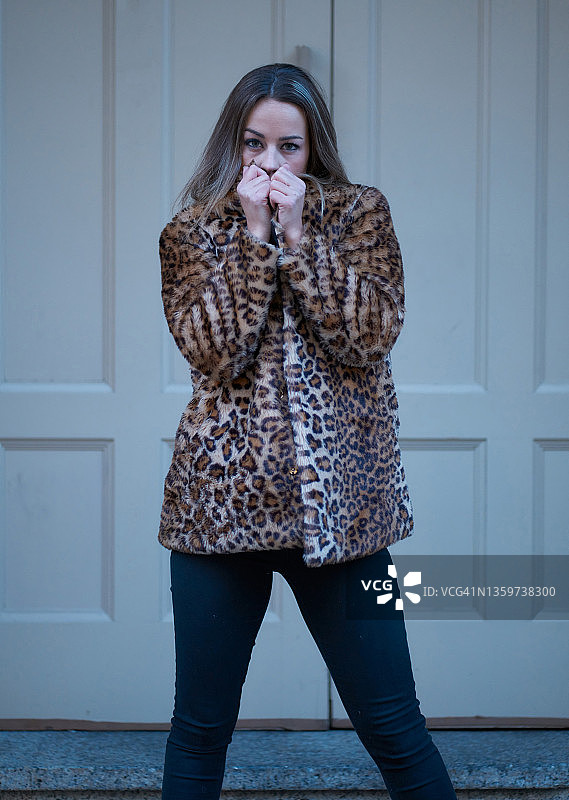 美丽的年轻女子的肖像穿着豹纹冬季大衣在街上。时尚的概念图片素材