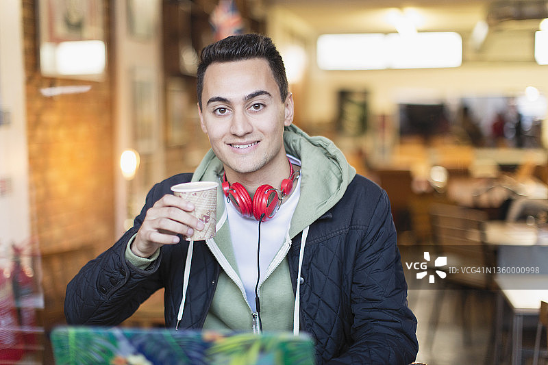 一名年轻的男大学生在咖啡厅里喝咖啡图片素材