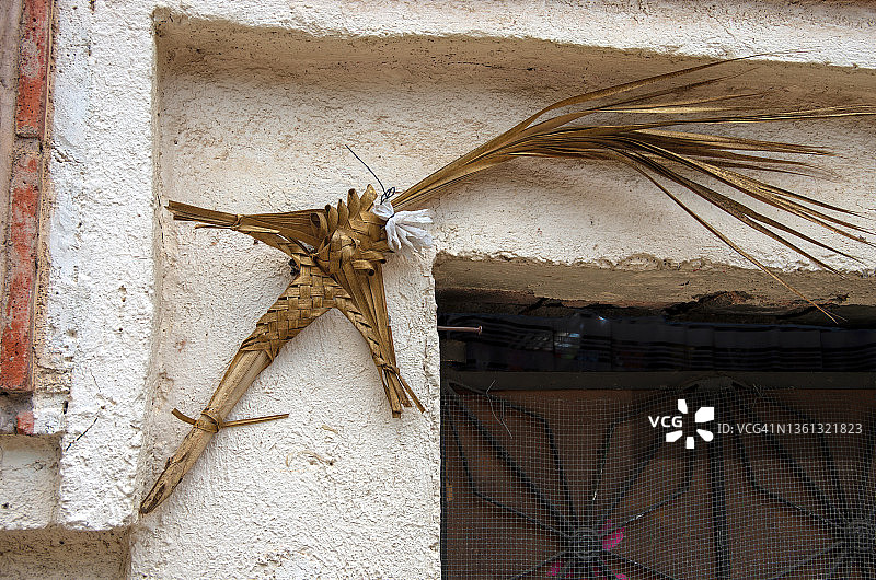 墨西哥莫雷洛斯州，Tepoztlán镇，一户人家门口上方编织的棕榈叶宗教十字架，来自于Semana Santa(圣周)的多明戈·拉莫斯(棕榈主日)仪式图片素材