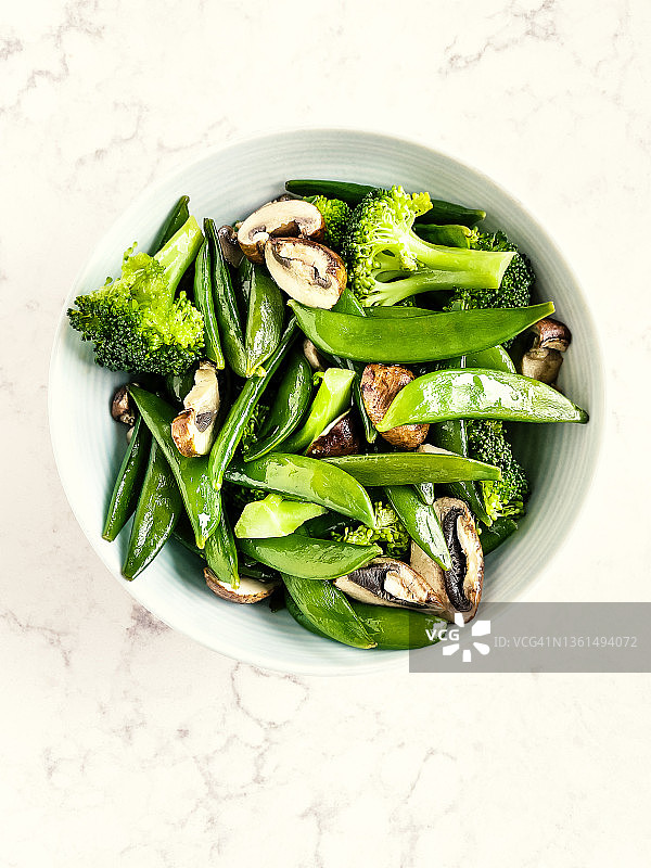 白色背景的蒸蔬菜(花椰菜，白糖豌豆)和蘑菇放在碗里图片素材