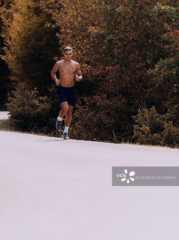 在美丽的自然环境中，一个运动的年轻人在山路上奔跑图片素材