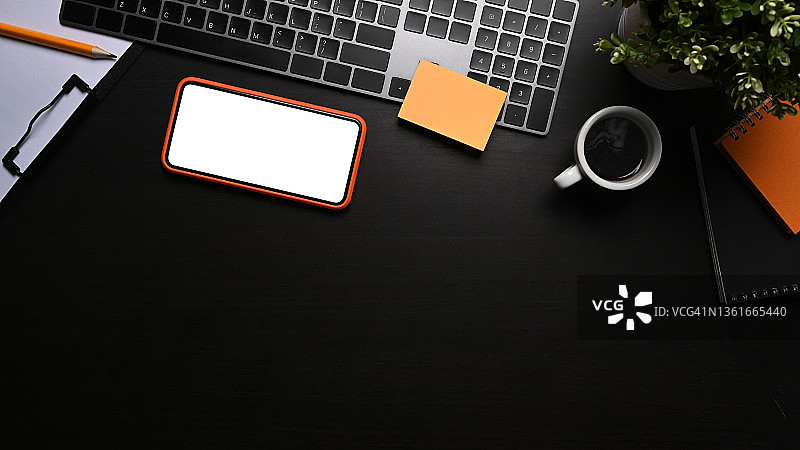 模拟智能手机空白显示屏，咖啡杯和键盘在黑色的桌子上。图片素材