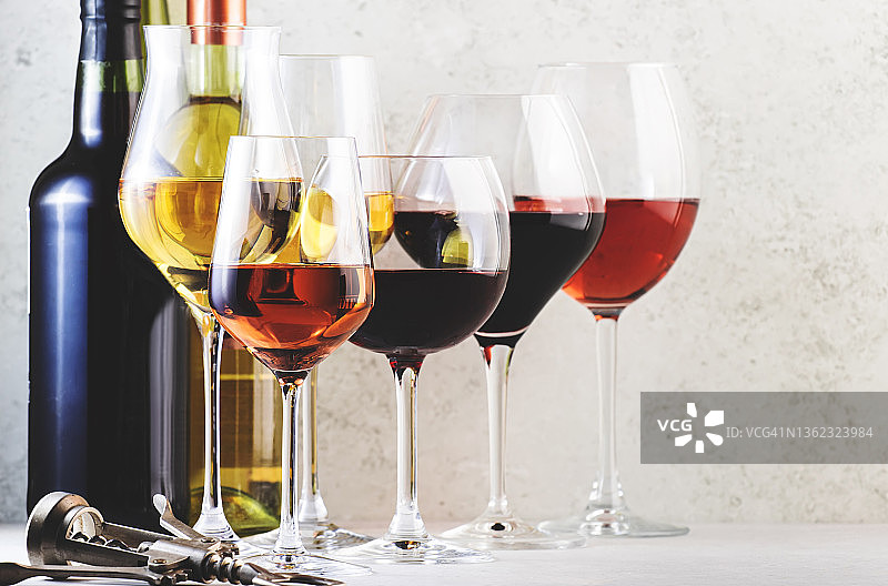 红、玫瑰和白葡萄酒酒杯设置在灰色的桌子背景上。品酒。强光和阴影图片素材
