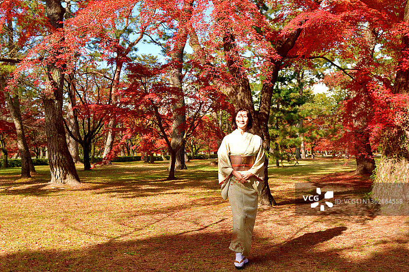 在京都，日本女子穿着和服享受美丽的秋叶图片素材