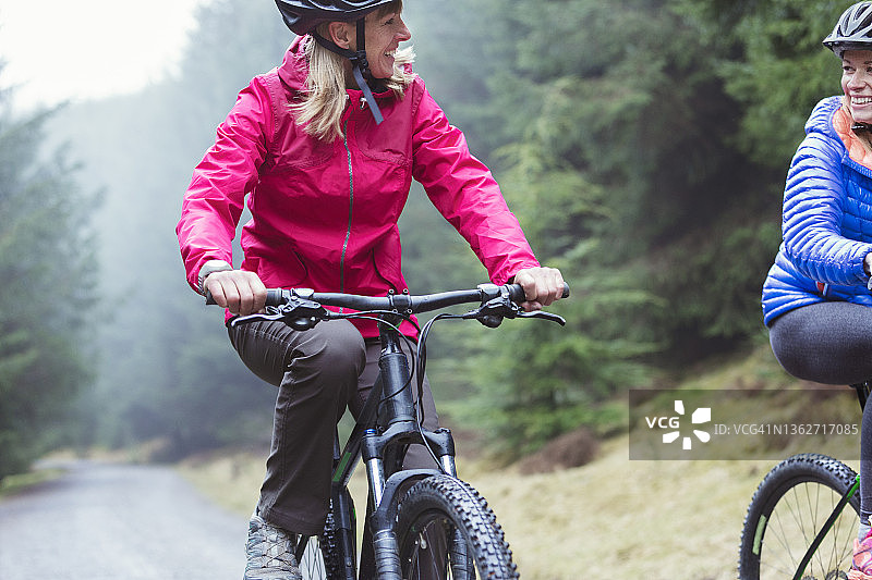 快乐的母女在森林小径上骑山地自行车图片素材