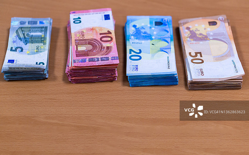 办公室的桌子上放着一捆捆的欧元钞票，同时清点当天的现金。图片素材