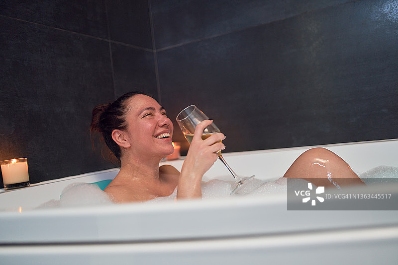 女人喝着酒在浴缸里放松图片素材