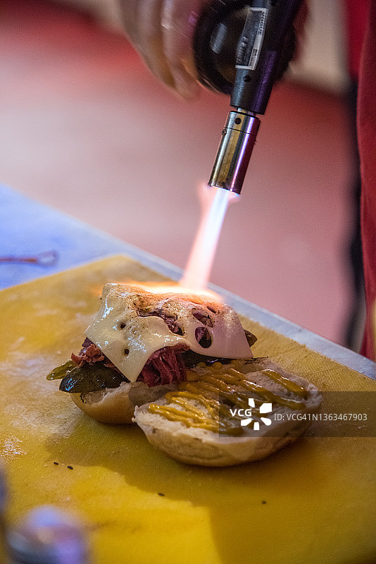 用火焰喷射器在咸牛肉百吉饼里融化奶酪图片素材