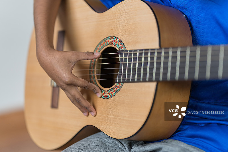 一个非裔美国男孩弹吉他的特写图片素材