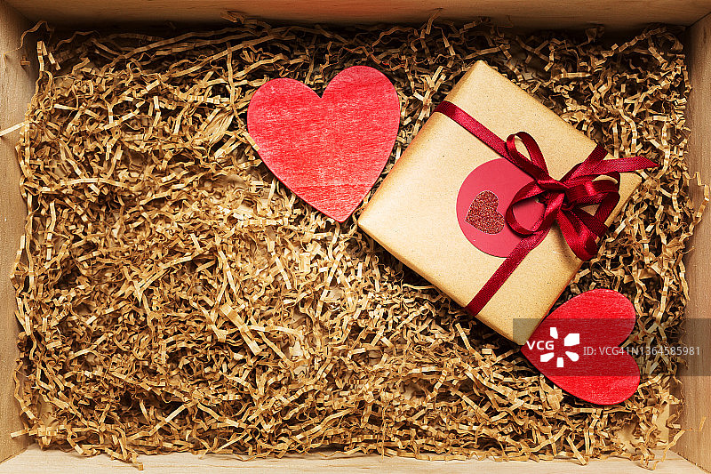 木盒与礼物包裹在棕色牛皮纸红色丝带，充满纸填料图片素材