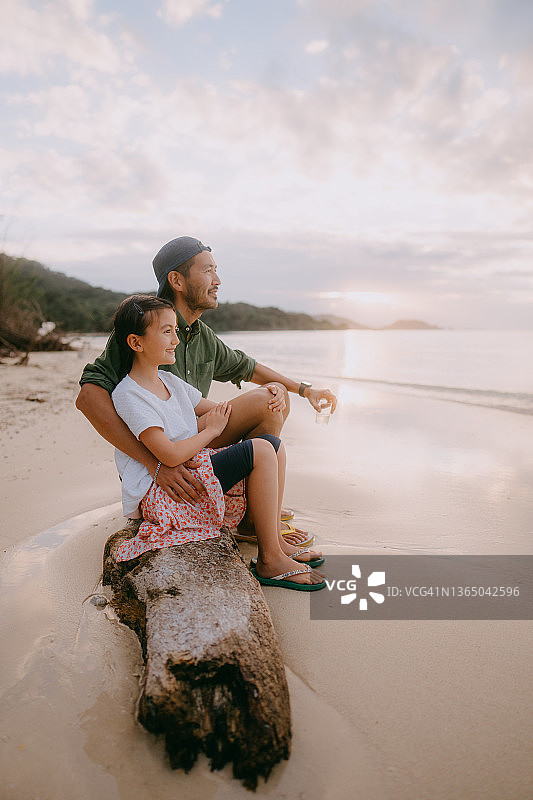 日落时分，父亲和小女儿坐在冲绳岛的海滩上图片素材