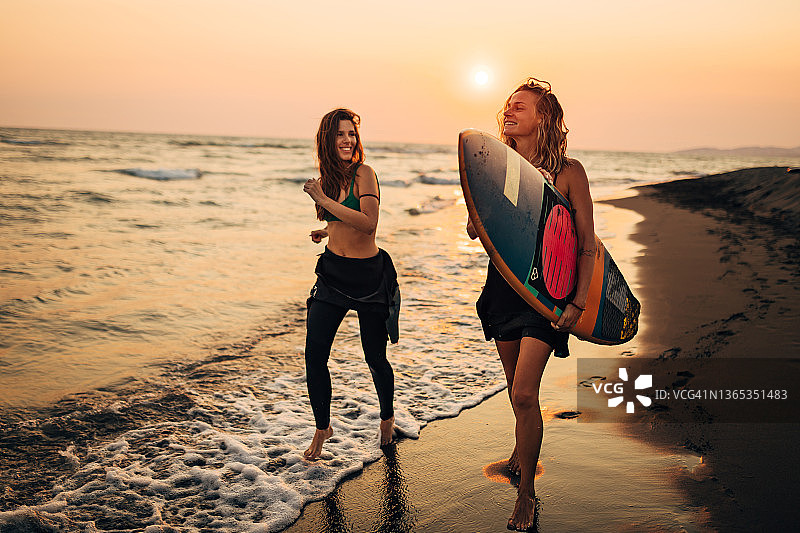 挑战!两个快乐的女人在海边度过了一天。他们正准备冲浪，享受海浪。图片素材