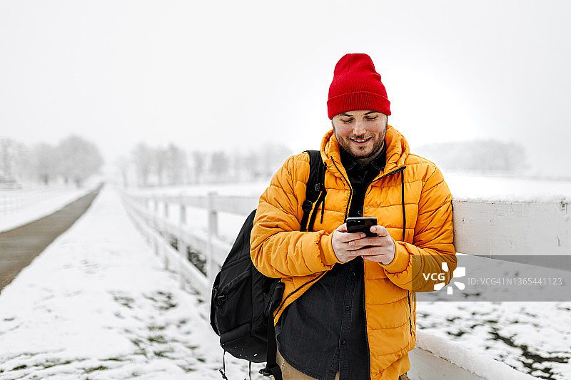 一名年轻人在下雪天在大自然中使用智能手机图片素材