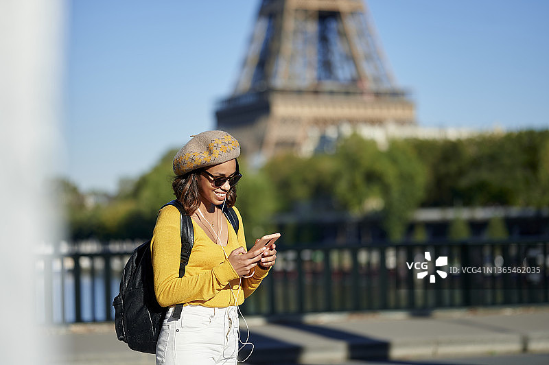 阳光明媚的一天，法国巴黎，一名女子在埃菲尔铁塔附近使用智能手机图片素材