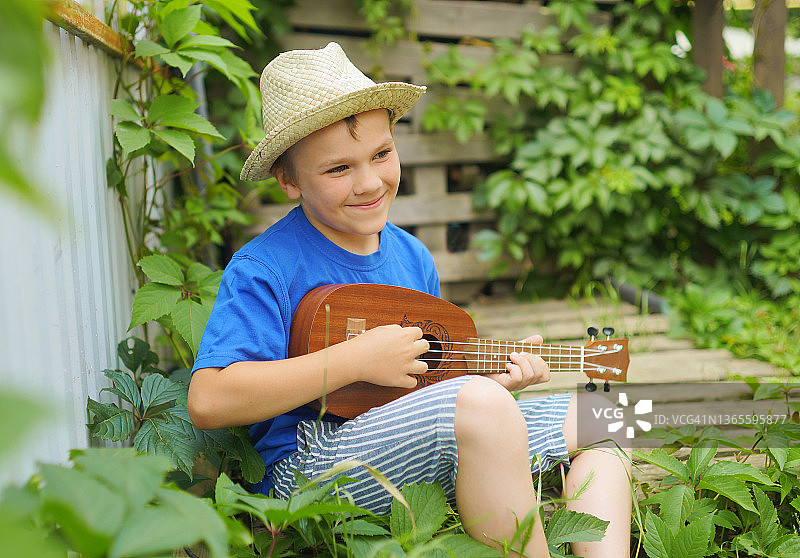 子尤克里里琴。乐器。夏天的季节。男孩的帽子。图片素材