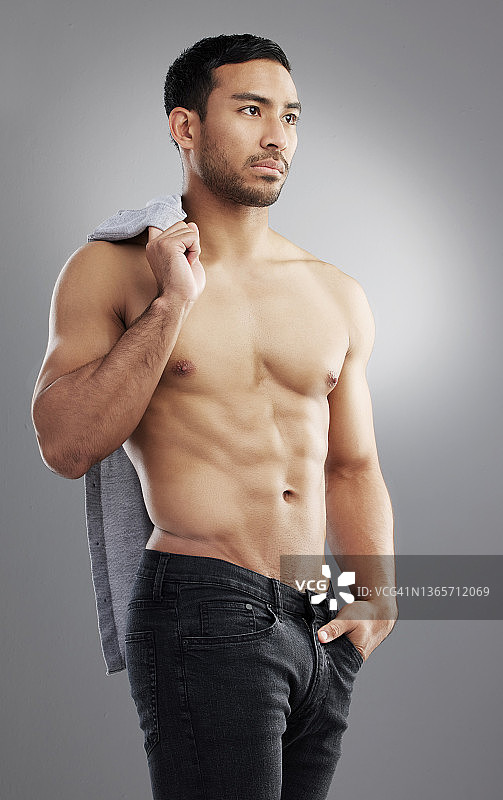 一名肌肉发达的年轻男子在灰色背景下摆姿势图片素材