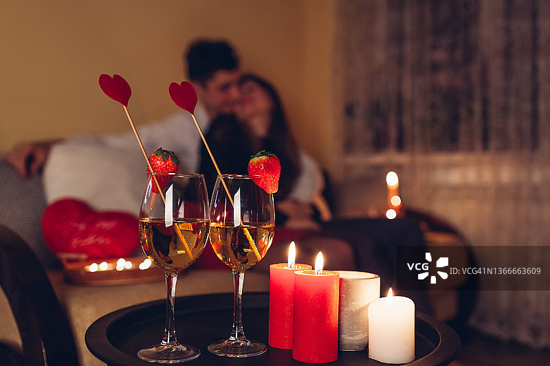 靠近节日饮料葡萄酒草莓和心形装饰的红色蜡烛。情人节情侣图片素材