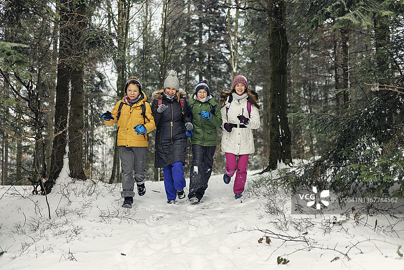 快乐的家庭徒步旅行在美丽的冬季森林图片素材