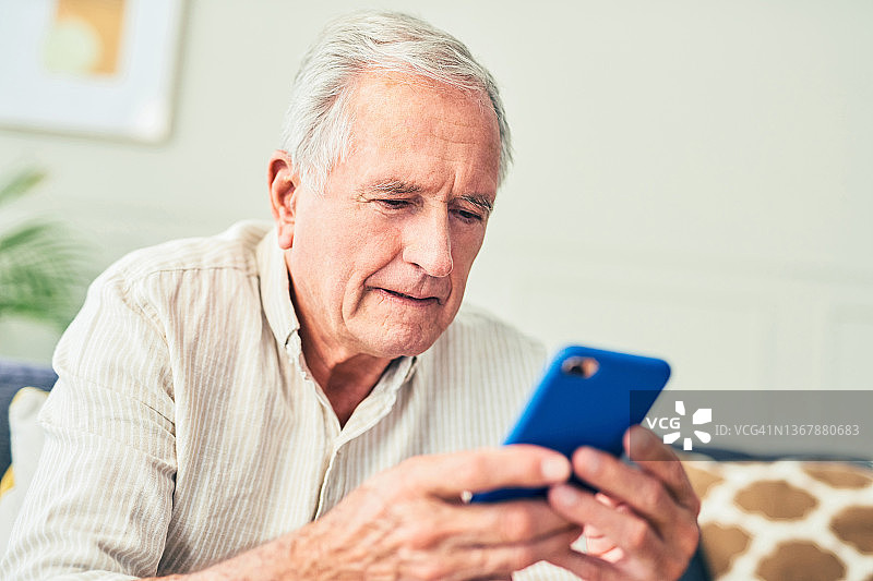 一名老人坐在家里用手机的照片图片素材