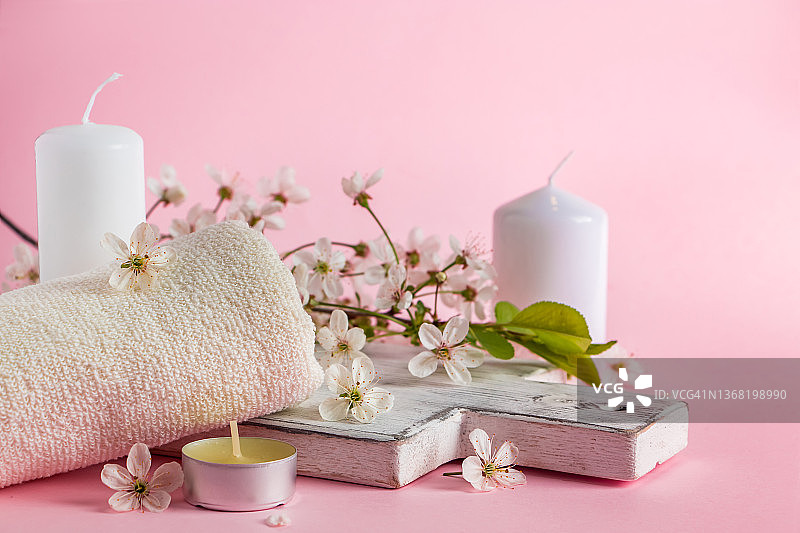 用于水疗和芳香疗法的天然化妆品。放松的概念。粉色背景的蜡烛，鲜花和毛巾。图片素材