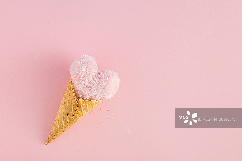 粉色背景下的心形冰淇淋蛋筒。最小的爱或情人节概念。平的。图片素材