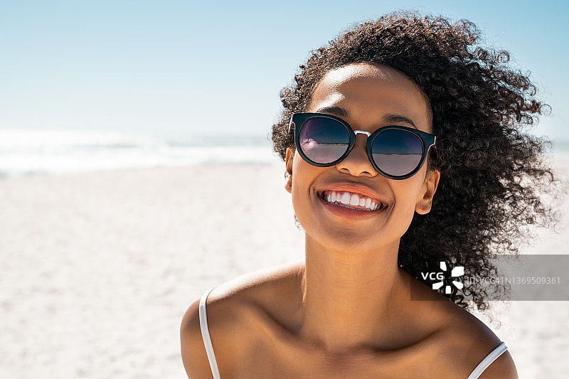 美丽的黑人妇女在海滩上戴着太阳镜图片素材