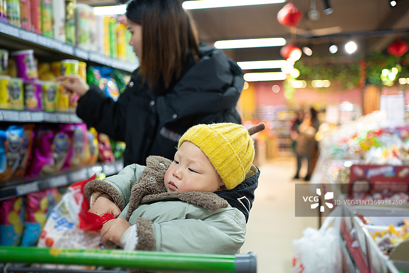 年轻的亚洲妇女带着孩子在超市购物图片素材