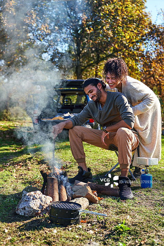 幸福的年轻夫妇在阳光明媚的秋野上享受篝火图片素材