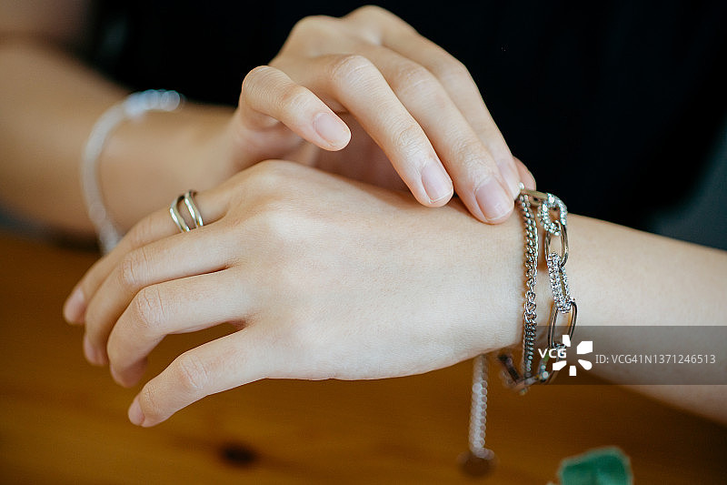 一名亚洲女性的手，展示着银戒指、手镯等奢侈饰品图片素材
