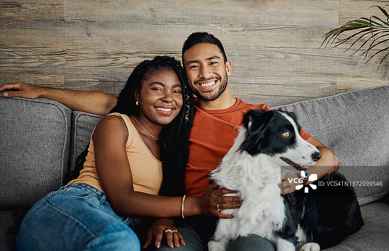 这张照片是一对幸福的年轻夫妇和他们的博德牧羊犬坐在家里的沙发上图片素材