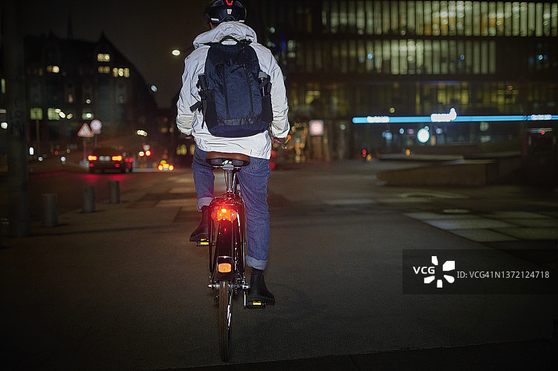 晚上在城市街道上骑自行车的年轻人图片素材